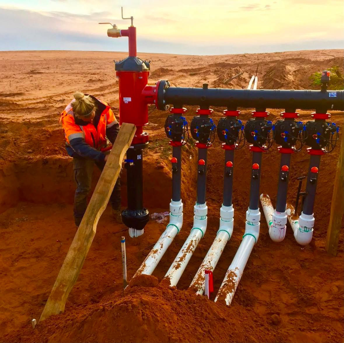 Pipeline manifold and pump infrastructure being installed in an excavation