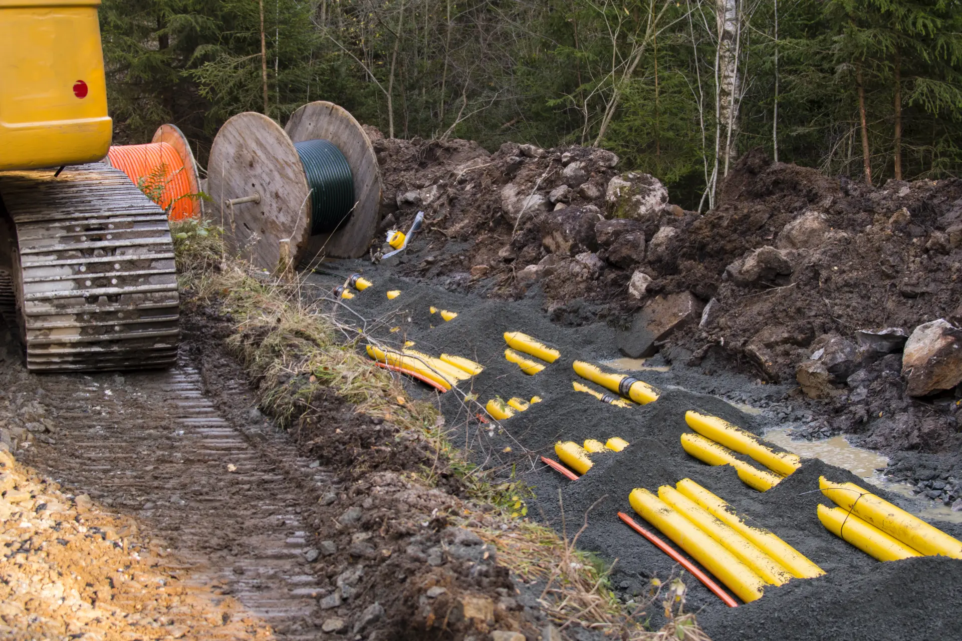 Cable ducts being laid in a trench through forest terrain